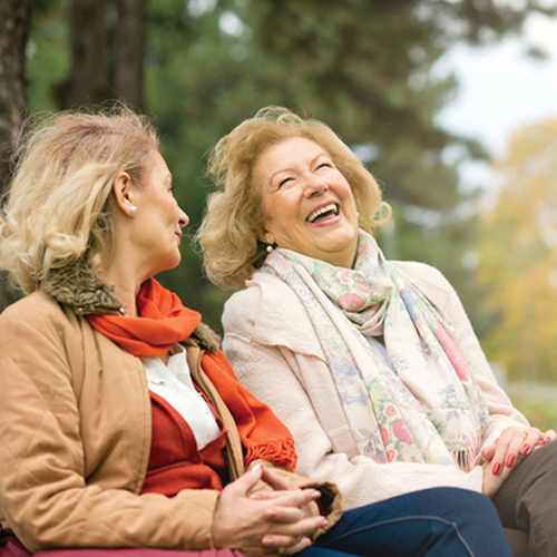 older women laughing on park bench